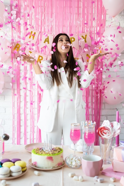 Mulher bonita comemorando festa de aniversário jogando confete rosa