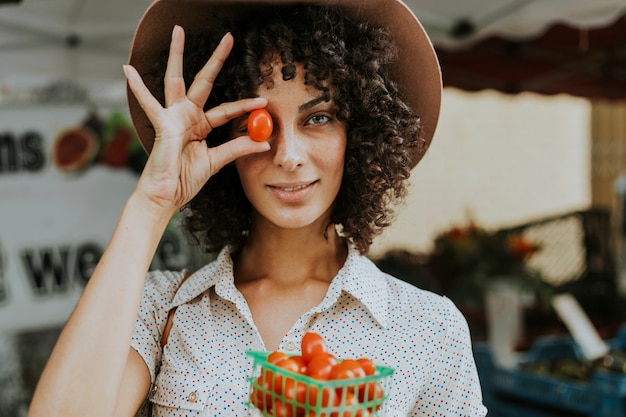 Mulher bonita comprando tomates em um mercado de agricultores