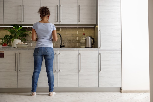 Mulher bonita cozinhando pratos deliciosos na cozinha de sua casa