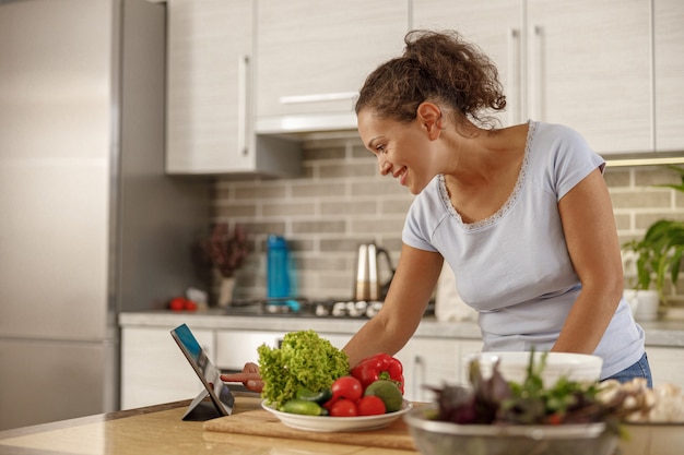 Mulher bonita cozinhando pratos deliciosos na cozinha de sua casa