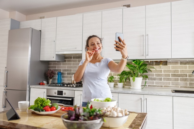 Mulher bonita cozinhando pratos deliciosos na cozinha de sua casa