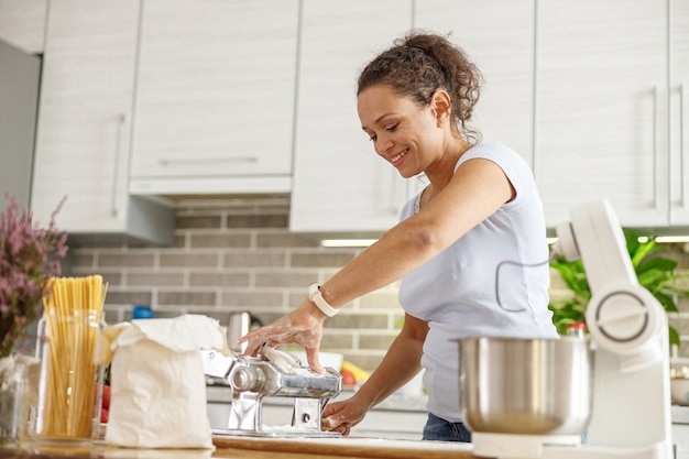 Mulher bonita cozinhando pratos deliciosos na cozinha de sua casa