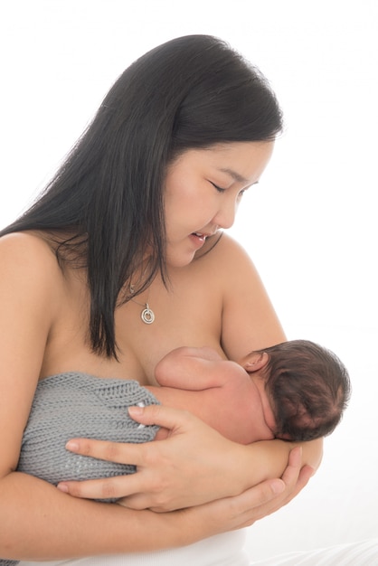 Mulher bonita da ásia segurando um bebê recém-nascido em seus braços