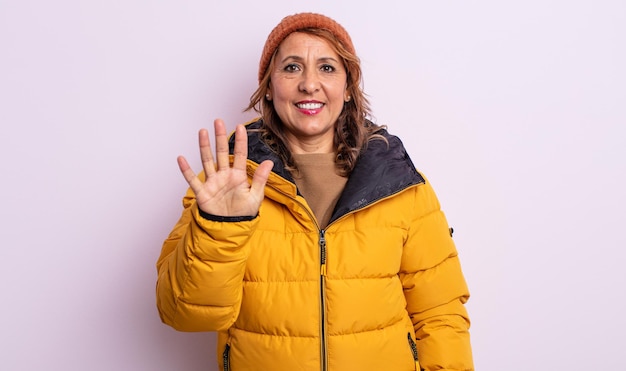 Mulher bonita da meia-idade sorrindo e parecendo amigável, mostrando o número cinco. conceito de inverno