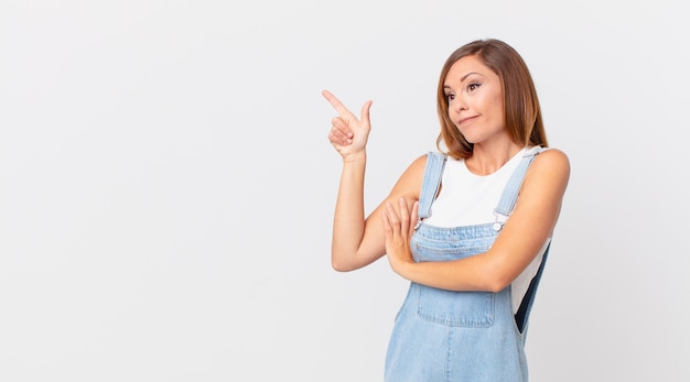 Mulher bonita dando de ombros, sentindo-se confusa e incerta e com um espaço de cópia ao lado