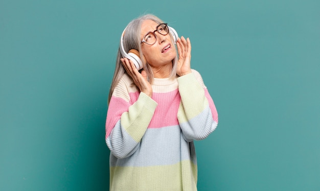 Mulher bonita de cabelo grisalho ouvindo música com fones de ouvido