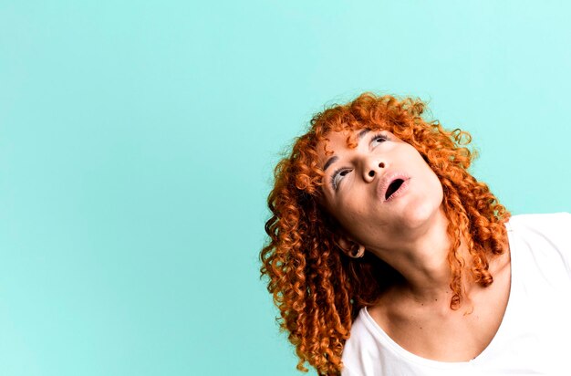 Mulher bonita de cabelo ruivo com um espaço de cópia ao lado apresentando algo