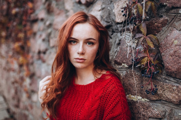 Mulher bonita de gengibre com sardas ao ar livre no parque outono. Rosto de mulher de beleza, conceito de beleza natural