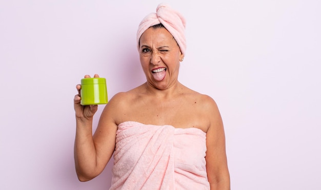 Mulher bonita de meia-idade com atitude alegre e rebelde, brincando e mostrando a língua. conceito de produto para banho e cabelo