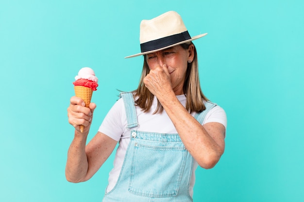 Mulher bonita de meia-idade com chapéu e segurando um sorvete. conceito de verão