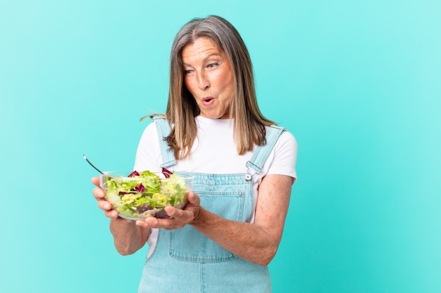 Mulher bonita de meia-idade com uma salada.