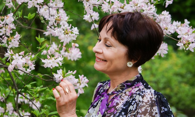 mulher bonita de meia idade no jardim de iac flores, ooking up, sorrindo