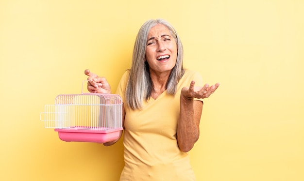 Mulher bonita de meia-idade parecendo desesperada, frustrada e estressada. conceito de gaiola ou prisão para animais de estimação