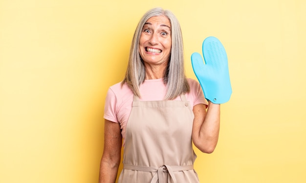 Mulher bonita de meia-idade parecendo feliz e agradavelmente surpresa. conceito de luva de forno