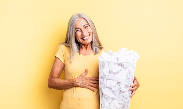 Mulher bonita de meia-idade rindo alto de alguma piada hilária. conceito de falha de bolas de papel