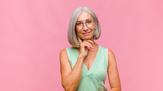 Mulher bonita de meia-idade rindo tímida e alegre, com uma atitude amigável e positiva, mas insegura