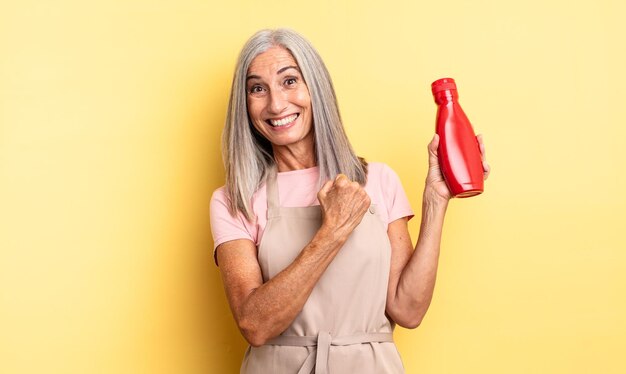 Mulher bonita de meia-idade se sentindo feliz e enfrentando um desafio ou comemorando. conceito de ketchup