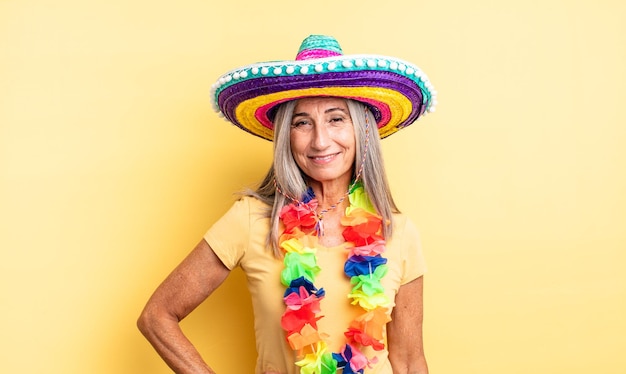 Mulher bonita de meia-idade, sorrindo alegremente com uma mão no quadril e confiante. conceito de festa mexicana