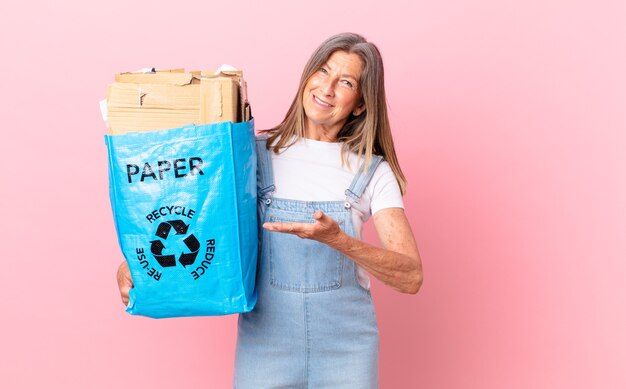 Mulher bonita de meia-idade sorrindo alegremente, sentindo-se feliz e mostrando um conceito de reciclagem de papelão.