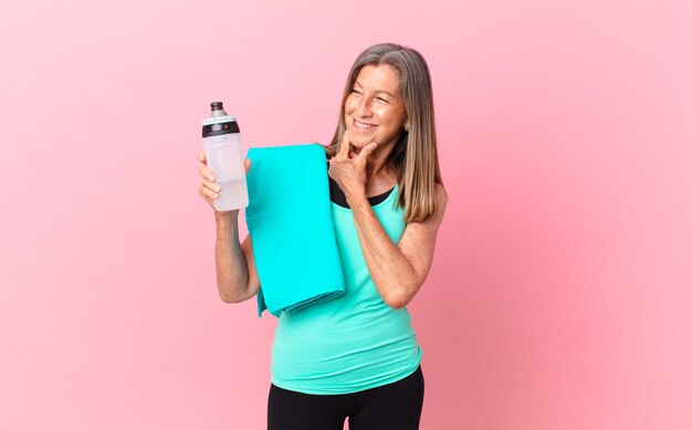 Mulher bonita de meia-idade, sorrindo com uma expressão feliz e confiante com a mão no queixo. conceito de fitness