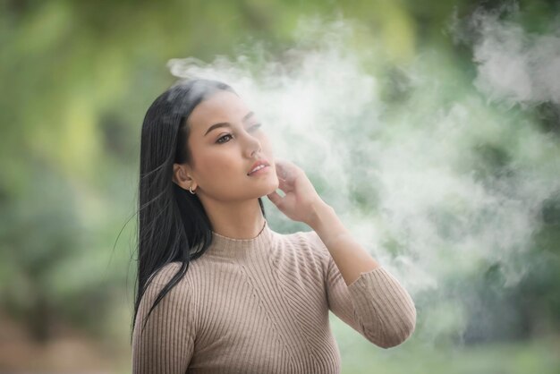 Foto mulher bonita de pé no meio da fumaça ao ar livre