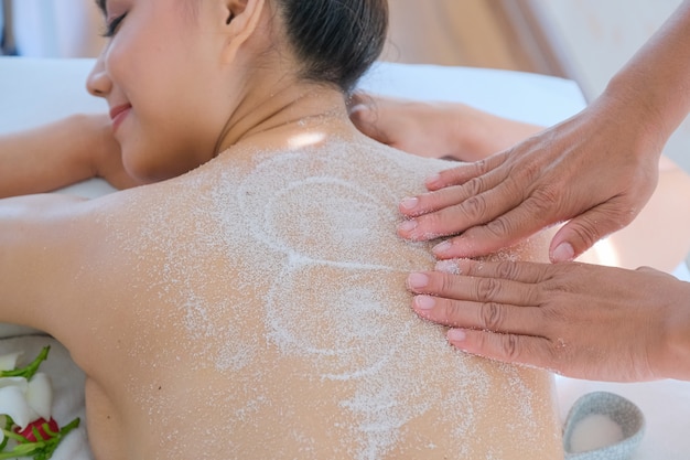 Mulher bonita de Ásia, desfrutando de uma massagem de sal esfrega no spa de saúde na Tailândia
