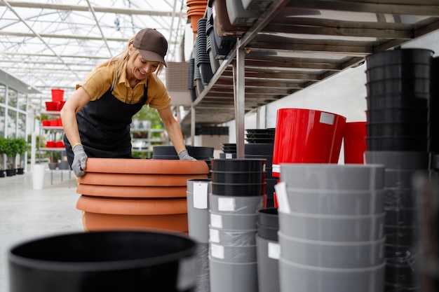 Mulher bonita de uniforme trabalhando em uma loja com vasos de flores