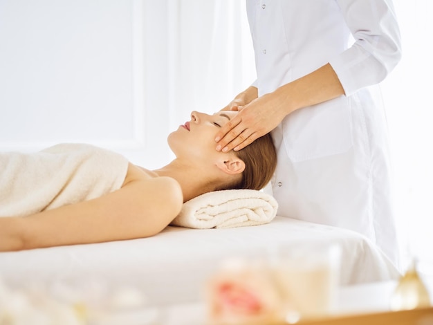 Mulher bonita, desfrutando de massagem facial com os olhos fechados. Conceito de tratamento de spa em medicina.