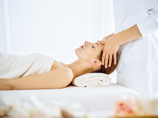 Mulher bonita, desfrutando de massagem facial com os olhos fechados no centro de spa. Relaxe o conceito de tratamento em medicina.