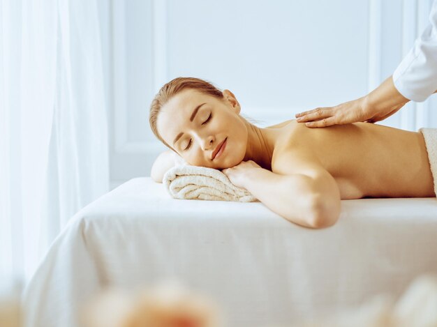 Mulher bonita, desfrutando de massagem nas costas com os olhos fechados. Conceito de tratamento de spa em medicina