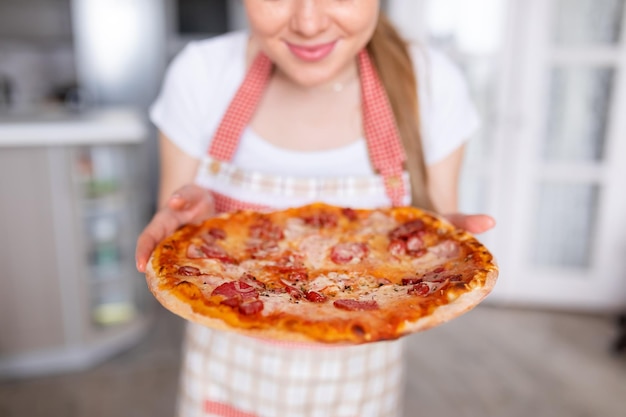 Mulher bonita desfrutando de pizza na cozinha moderna