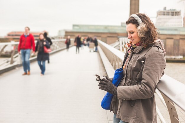 Mulher bonita, digitando no telefone inteligente em Londres