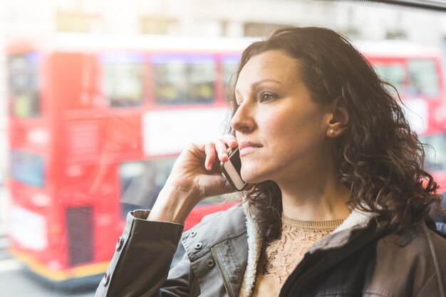 Mulher bonita, digitando no telefone inteligente enquanto pendulares em Londres