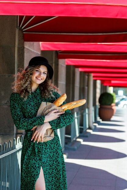 Mulher bonita do retrato com baguete nas mãos na rua. Mulher vestida em estilo francês