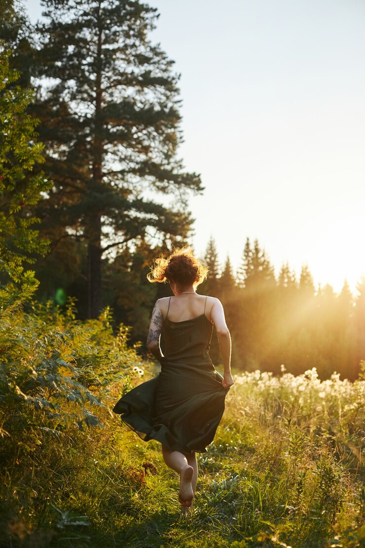 Mulher bonita do retrato na floresta ao pôr do sol. Mulher está descansando na natureza, um retrato de arte sob os raios do sol