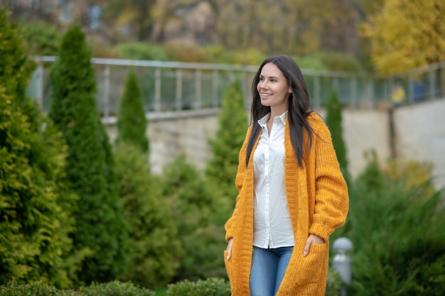 Mulher bonita e agradável em pé no jardim enquanto aprecia seu passeio