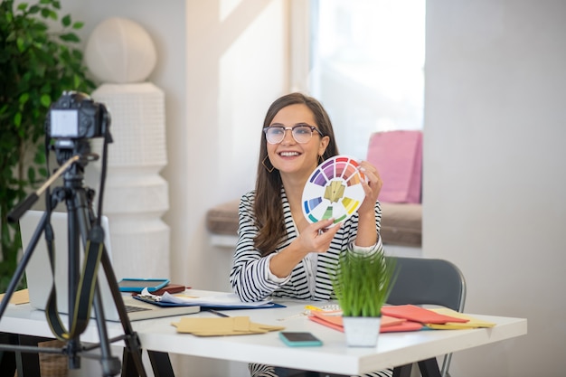 Mulher bonita e alegre sorrindo enquanto fala sobre design para a câmera