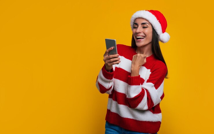 Foto mulher bonita e animada aos gritos com o smartphone nas mãos por ter ganhado algum presente na época do natal