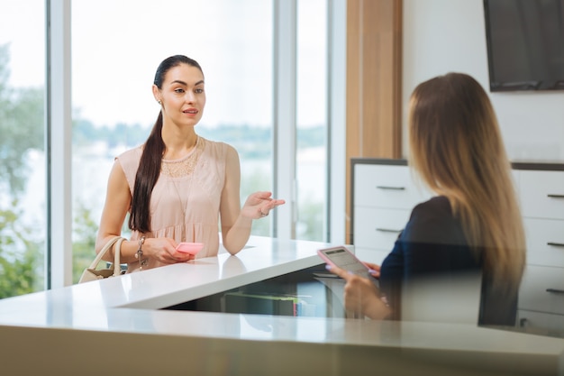 Mulher bonita e bonita olhando para o administrador enquanto faz uma pergunta