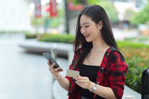 Mulher bonita e charmosa usando telefone celular e cartão de crédito para transferir dinheiro via celular