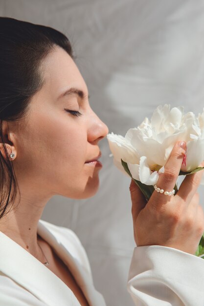 Mulher bonita e deslumbrante com flores de peônias. fechar-se