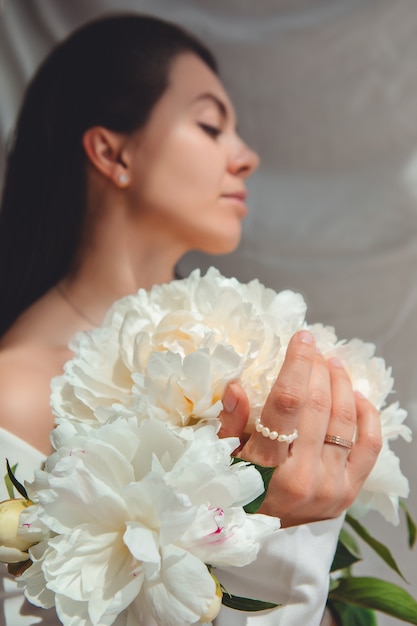 Mulher bonita e deslumbrante com flores de peônias. fechar-se