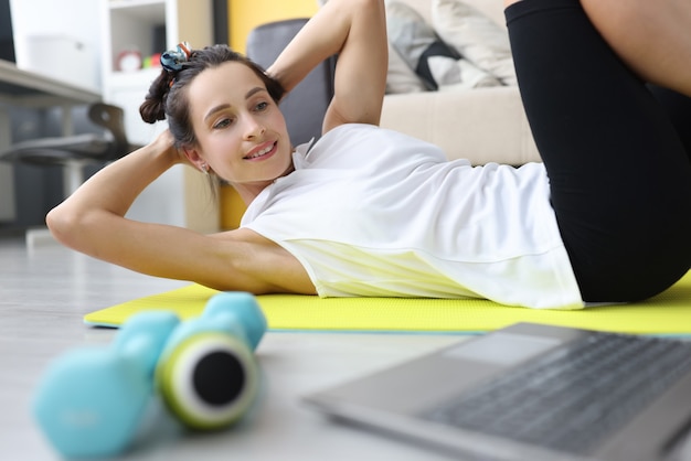 Mulher bonita e desportiva fazendo exercícios de fitness para a imprensa em casa