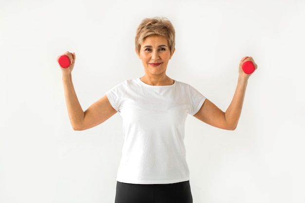 Mulher bonita e elegante em camiseta branca para esporte com halteres