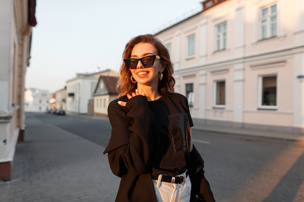 Mulher bonita e elegante em roupas pretas da moda caminhando na rua