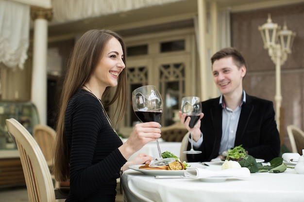 Mulher bonita e homem no restaurante, segurando o copo de vinho