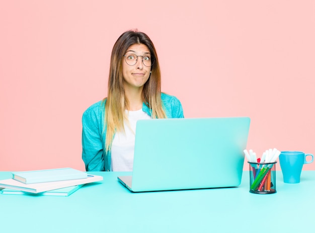 Mulher bonita e jovem trabalhando com um laptop se sentindo triste e estressada, chateada por causa de uma surpresa ruim, com um olhar negativo e ansioso