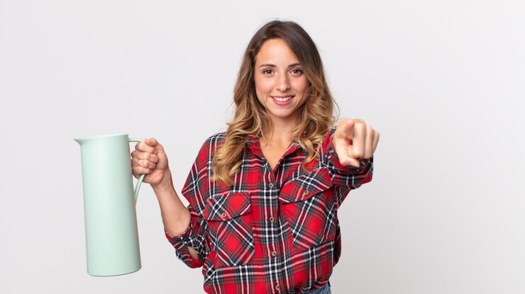 Foto mulher bonita e magra apontando para a câmera, escolhendo você e segurando uma garrafa térmica de café