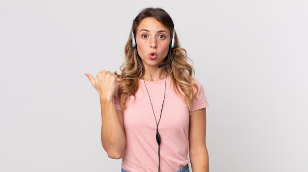 Mulher bonita e magra parecendo espantada com a descrença .assistente do operador com um fone de ouvido