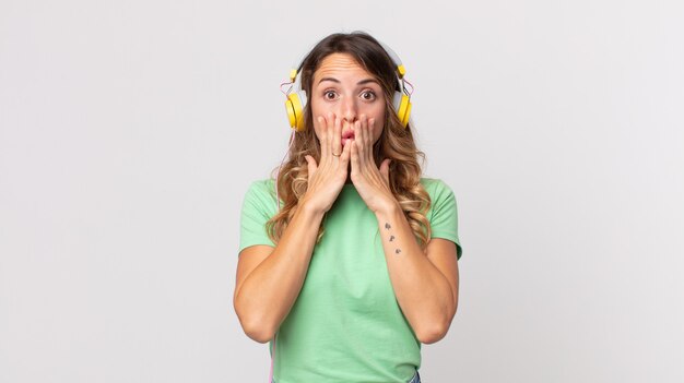 Mulher bonita e magra se sentindo chocada e com medo de ouvir música com fones de ouvido